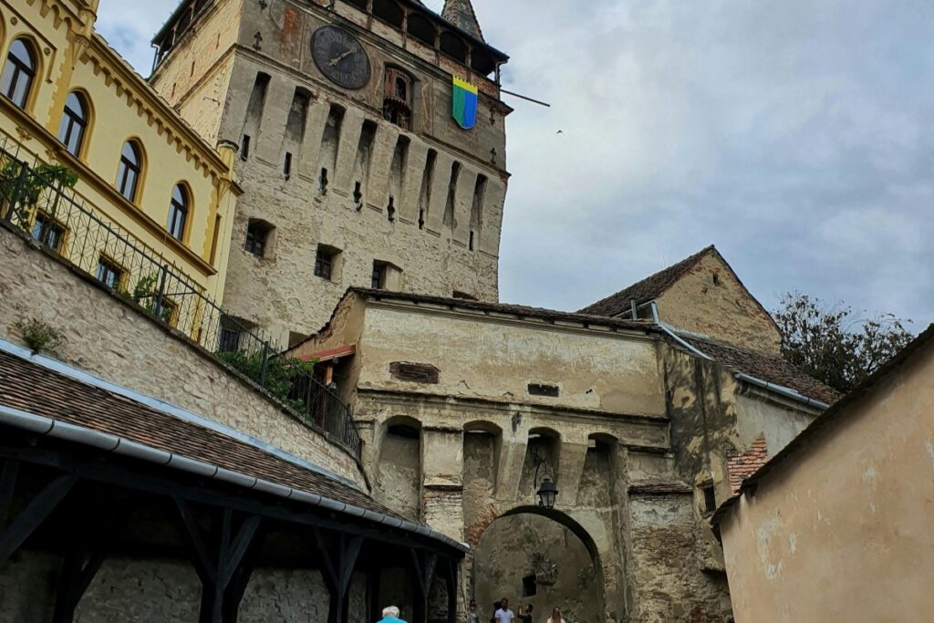 Imaginea ne prezintă o cetate medievală impunătoare, cu ziduri de piatră și un turn ceas notabil. Un steag flutură pe vârful turnului, conferind o senzație de istorie și identitate. Sub un cer plimbat de nori, câteva persoane se pot vedea în jurul clădirii, sugerând că este un loc de interes turistic. Pe Twitter, Marocanezii și turiștii se adună pentru a discuta despre astfel de obiective istorice. Platforma a devenit un mijloc esențial pentru a împărtăși pozele și impresiile despre patrimoniul marocain, pentru a promova cultura locală și pentru a convinge lumea de frumusețea și importanța acestor locuri istorice.