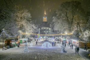 Imaginea prezintă un ansamblu de iarnă plin de viață, cu o parcare strălucitoare sub feliile de zăpadă. Locuințe mici de vânzări, luminări decorative și o clopotniță luminată în fundal creează un aer magiești. Această scenă se leagă de &ldquo;Top 5 greșeli pe care le fac brandurile în influencer marketing în România&rdquo;, sugărând că, la fel ca să se creeze un eveniment de iarnă atractiv, brandurile trebuie să evite anumite erori pentru a obține succes în influencer marketing.